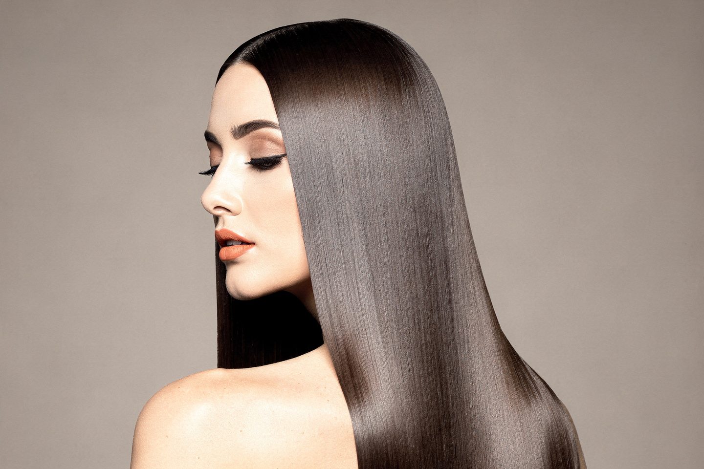 Femme de dos, visage de profil, longs cheveux lisses et brillants, sur fond uni